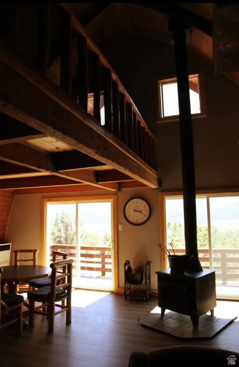 Dining area with plenty of natural light, dark hardwood / wood-style flooring, a towering ceiling, and a wood stove
