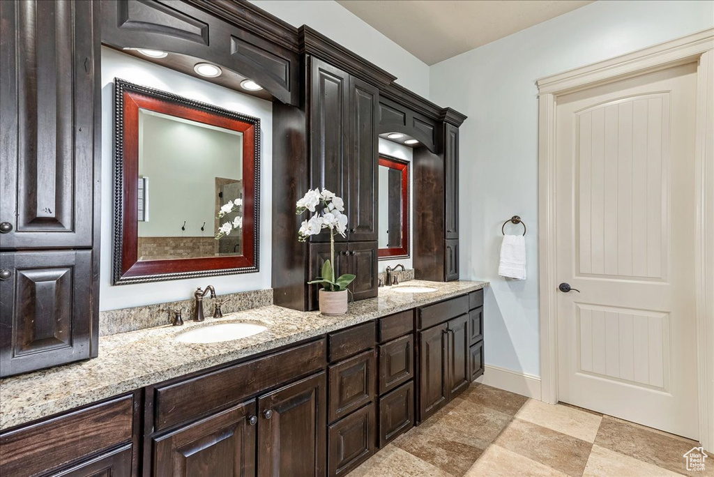 Bathroom with dual sinks, vanity with extensive cabinet space, and tile floors