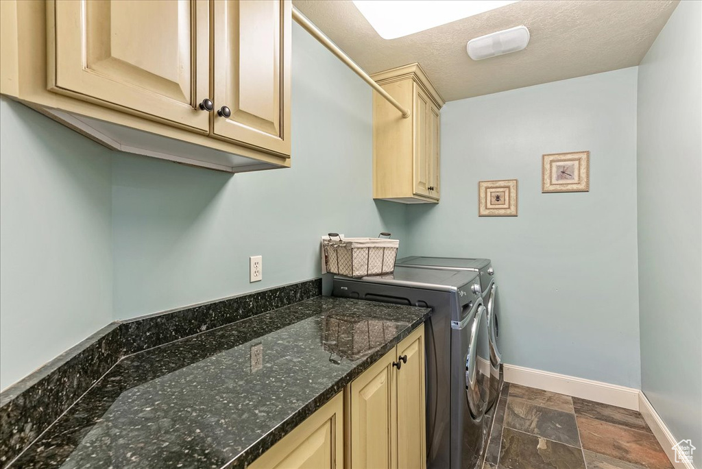Laundry area featuring cabinets, dark tile flooring, independent washer and dryer, and a textured ceiling