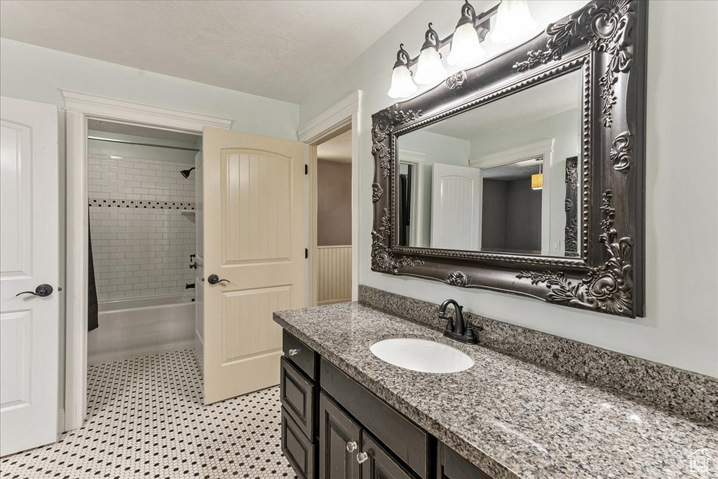 Bathroom with tile floors, vanity, and shower / tub combo with curtain