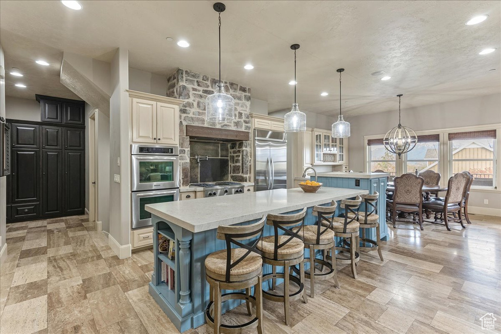 Kitchen featuring a center island, stainless steel appliances, a kitchen bar, and hanging light fixtures