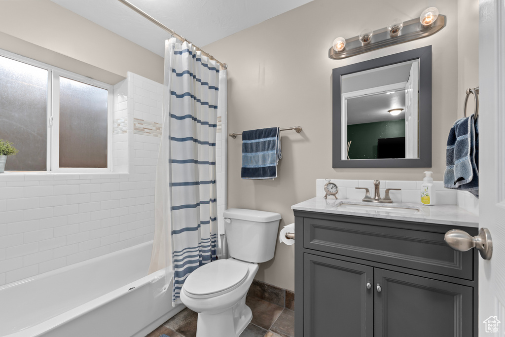 Full bathroom featuring oversized vanity, toilet, tile floors, and shower / tub combo with curtain