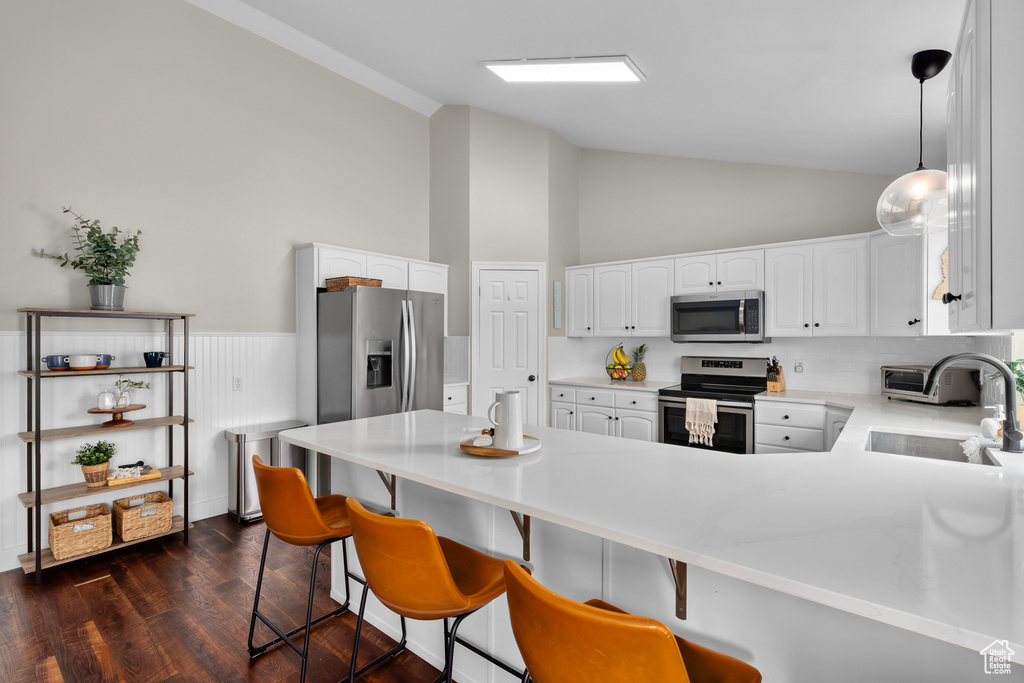 Kitchen featuring appliances with stainless steel finishes, a kitchen breakfast bar, sink, and pendant lighting