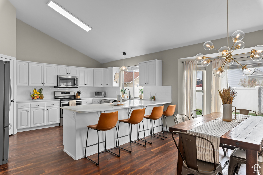 Kitchen with pendant lighting, appliances with stainless steel finishes, tasteful backsplash, and white cabinetry