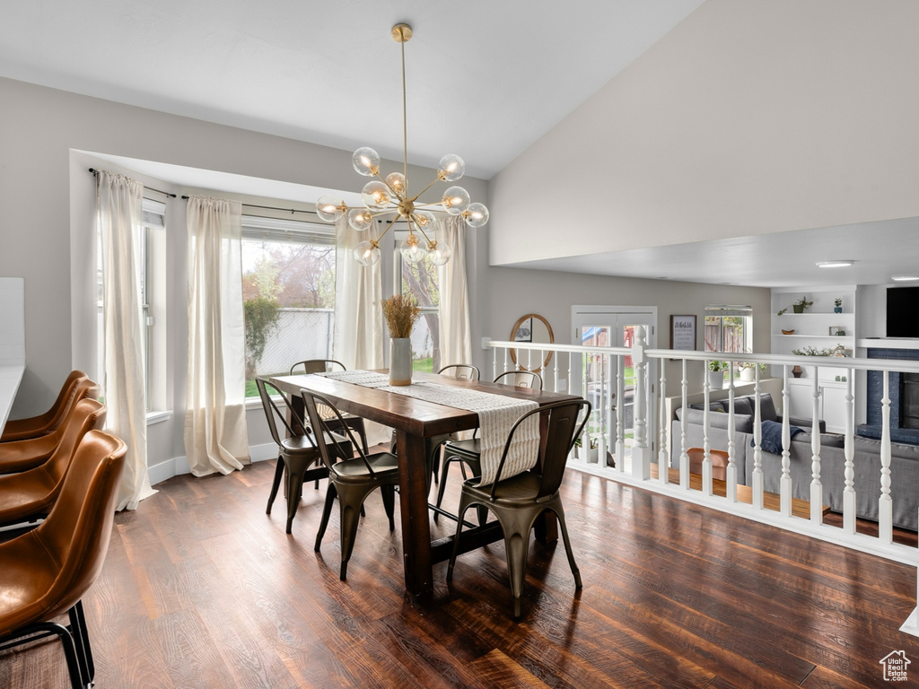 Dining area featuring dark hardwood / wood-style floors, high vaulted ceiling, built in shelves, and a chandelier