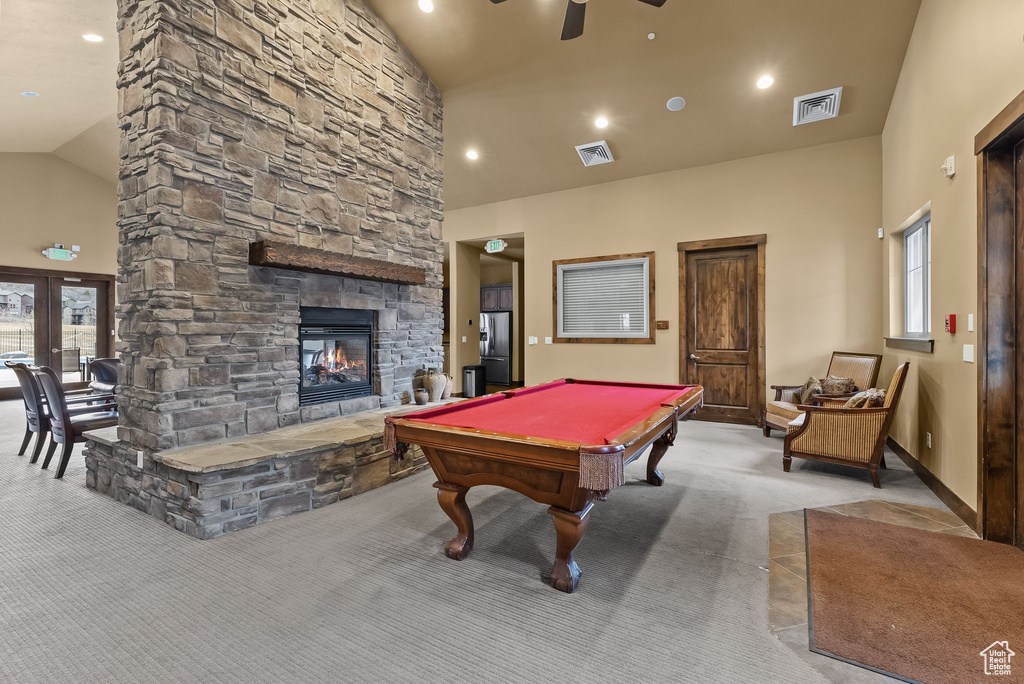 Recreation room with ceiling fan, a stone fireplace, light carpet, high vaulted ceiling, and pool table