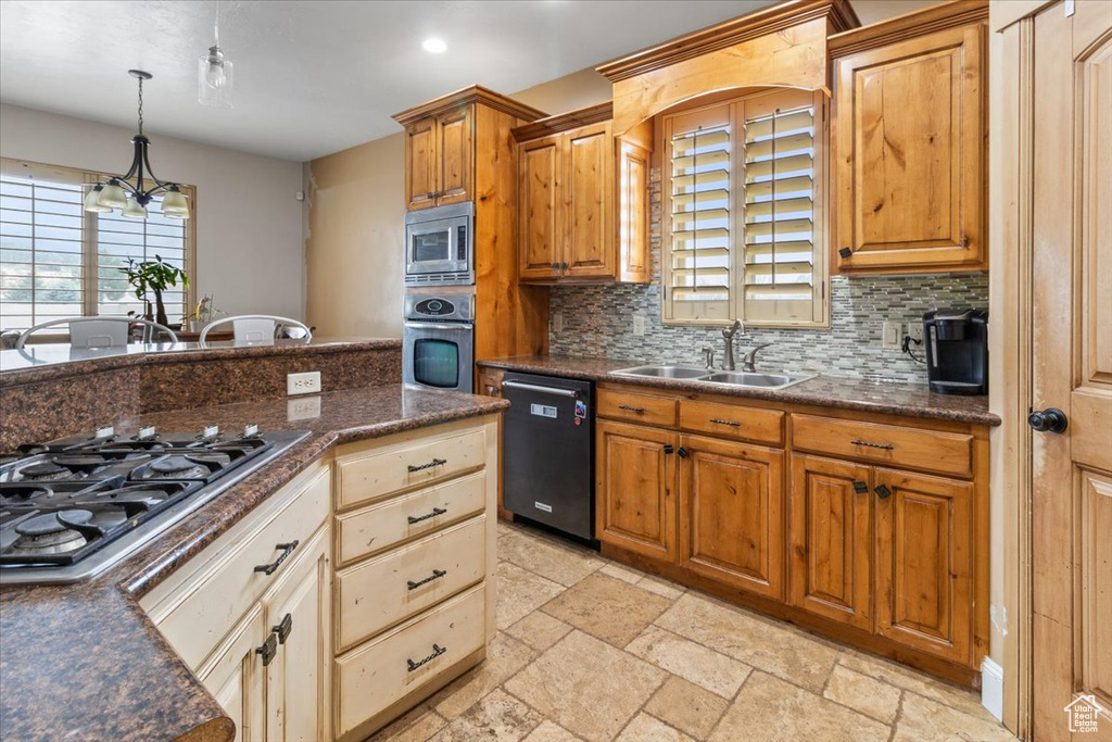Kitchen featuring backsplash, hanging light fixtures, stainless steel appliances, sink, and light tile floors