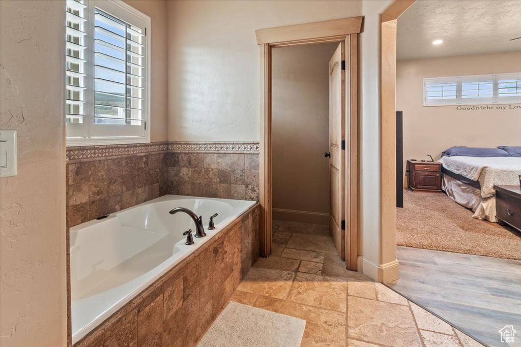 Bathroom featuring tile flooring, plenty of natural light, and tiled tub