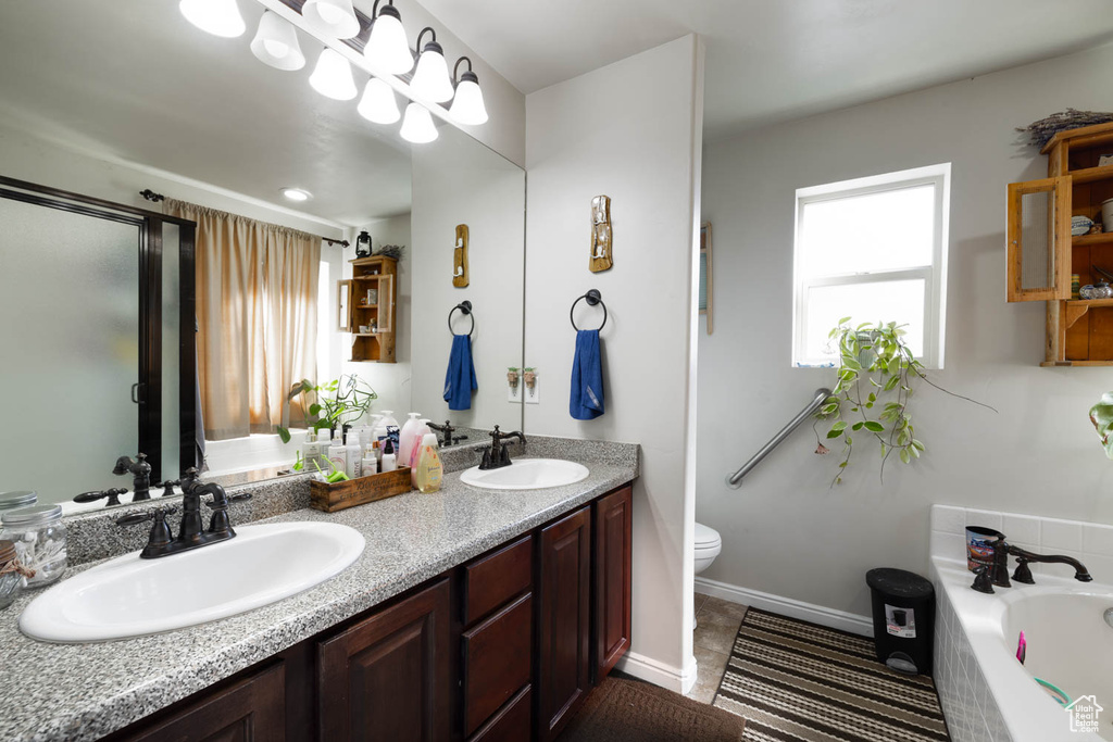 Bathroom featuring tile flooring, a bath, large vanity, dual sinks, and toilet