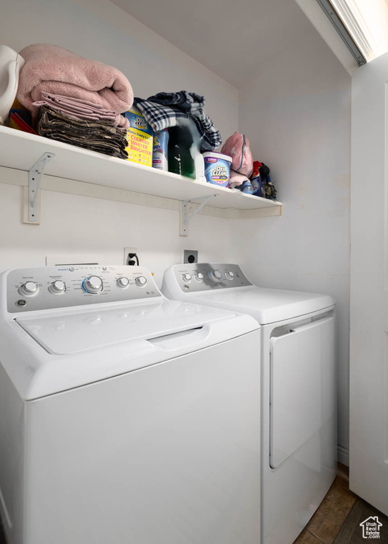 Clothes washing area with washing machine and dryer, dark tile floors, and electric dryer hookup