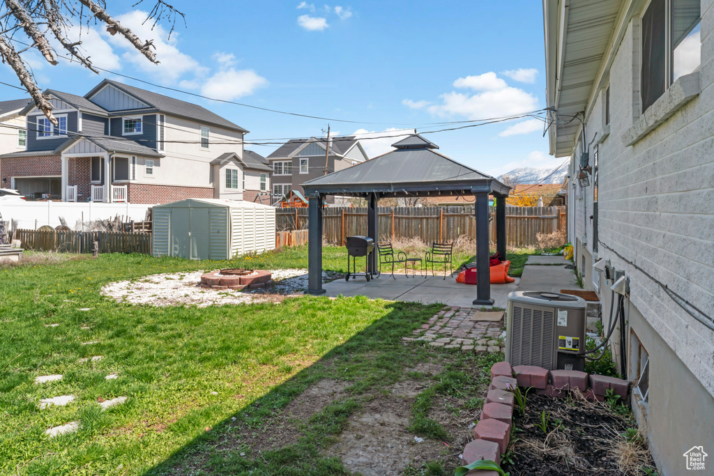 View of yard with a gazebo, a fire pit, a shed, a patio, and central air condition unit