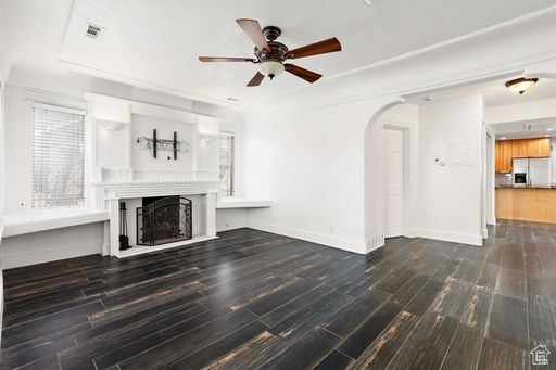 Unfurnished living room featuring ceiling fan and dark hardwood / wood-style flooring