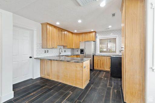 Kitchen with sink, tasteful backsplash, dark wood-type flooring, kitchen peninsula, and stone counters