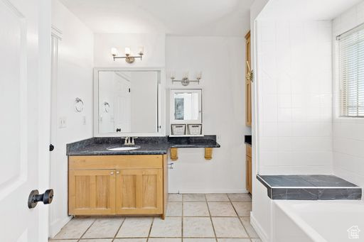 Bathroom with tile flooring, a bath, and vanity