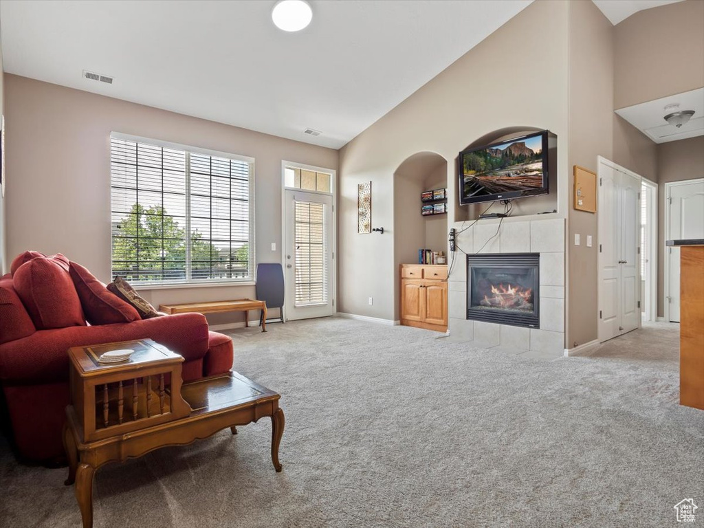 Living room with light carpet, high vaulted ceiling, and a fireplace