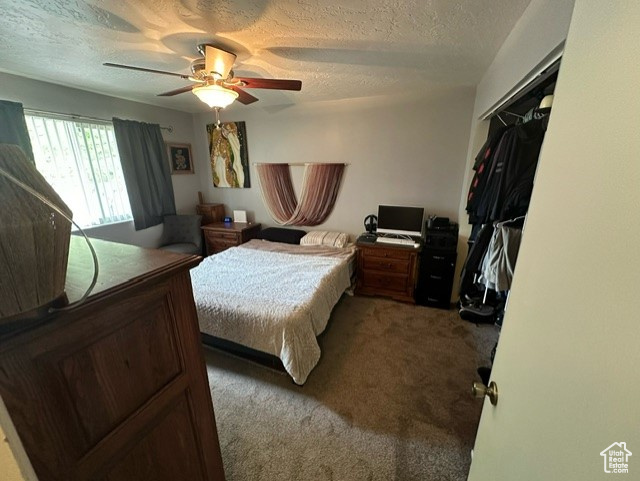 Carpeted bedroom with a closet, ceiling fan, and a textured ceiling
