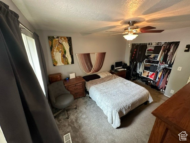Bedroom with a textured ceiling, ceiling fan, and carpet