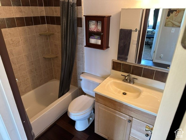 Full bathroom featuring backsplash, shower / tub combo, toilet, and vanity