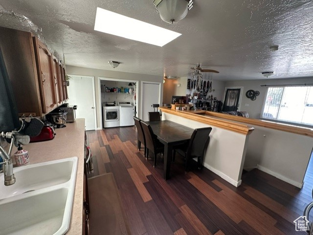 Kitchen with dark hardwood / wood-style flooring, washing machine and clothes dryer, sink, ceiling fan, and a textured ceiling