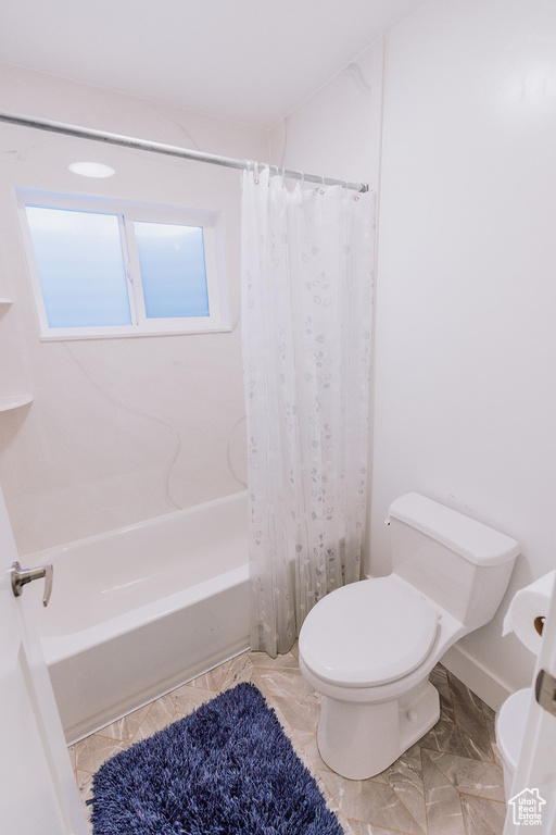 Bathroom with tile flooring, shower / tub combo, and toilet