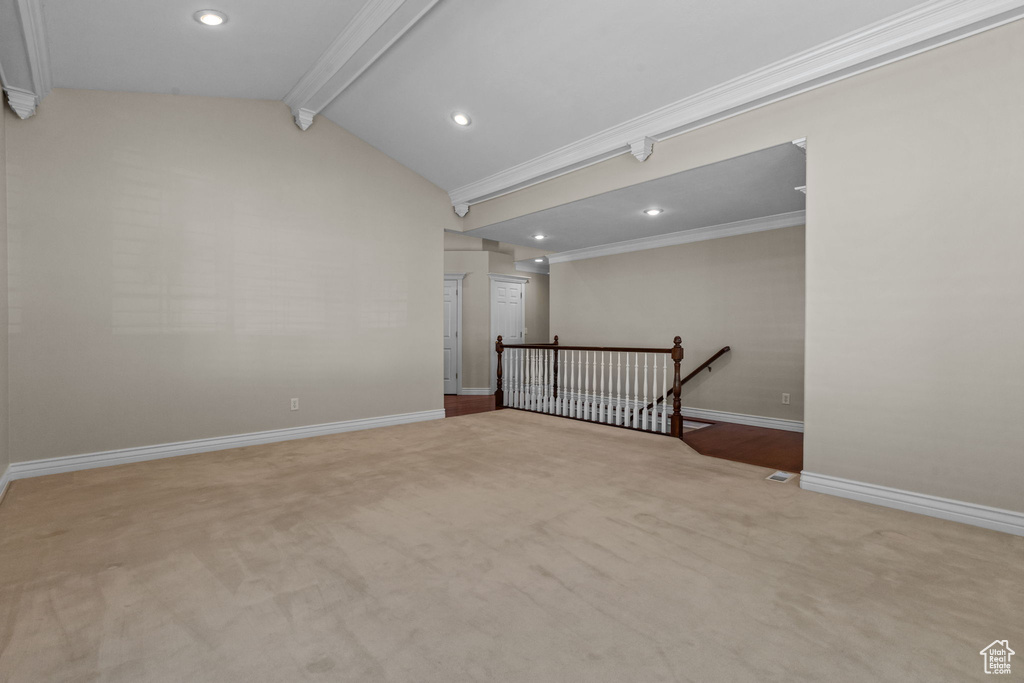 Carpeted spare room with crown molding and vaulted ceiling with beams