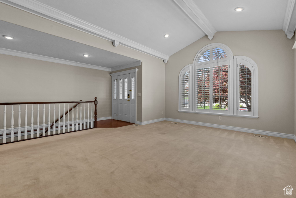 Carpeted empty room with crown molding and vaulted ceiling with beams