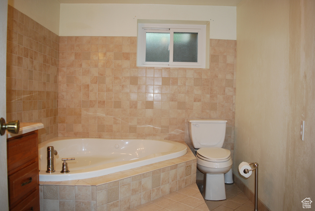 Bathroom featuring tile walls, toilet, tile floors, and tiled bath