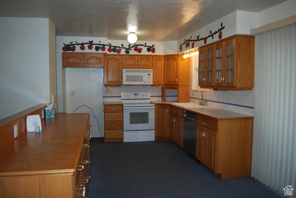 Kitchen featuring backsplash, white appliances, a textured ceiling, sink, and dark carpet