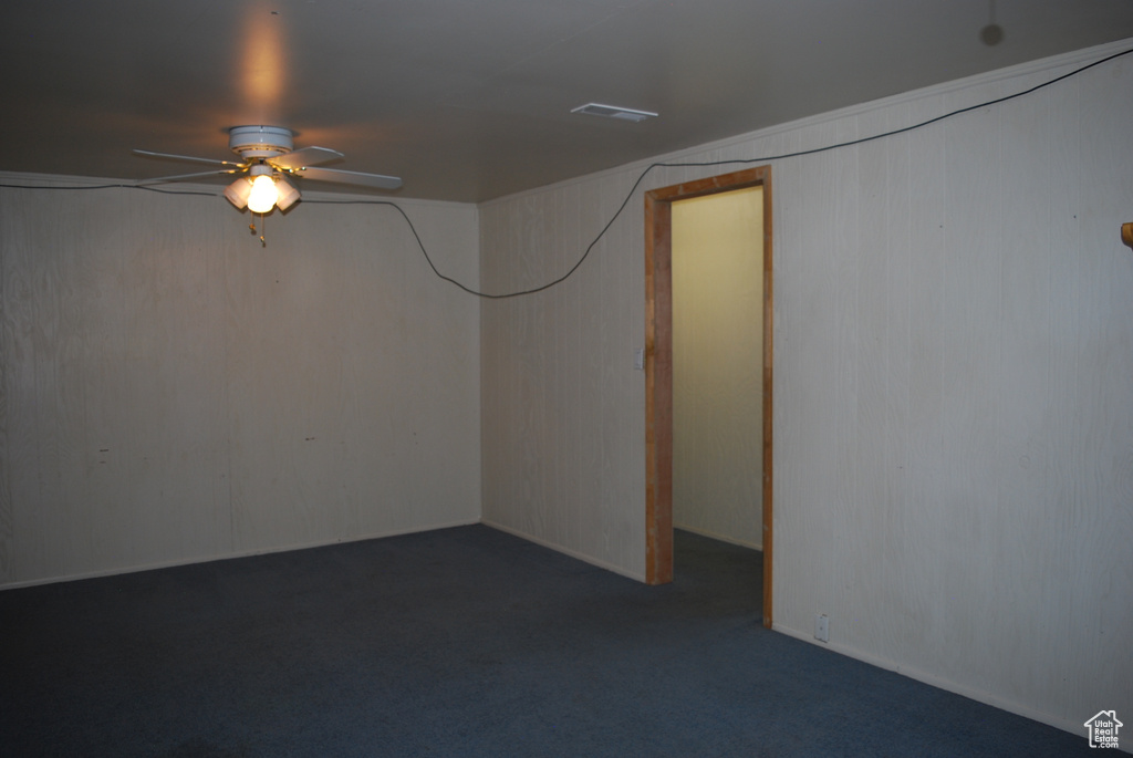 Basement with dark colored carpet and ceiling fan