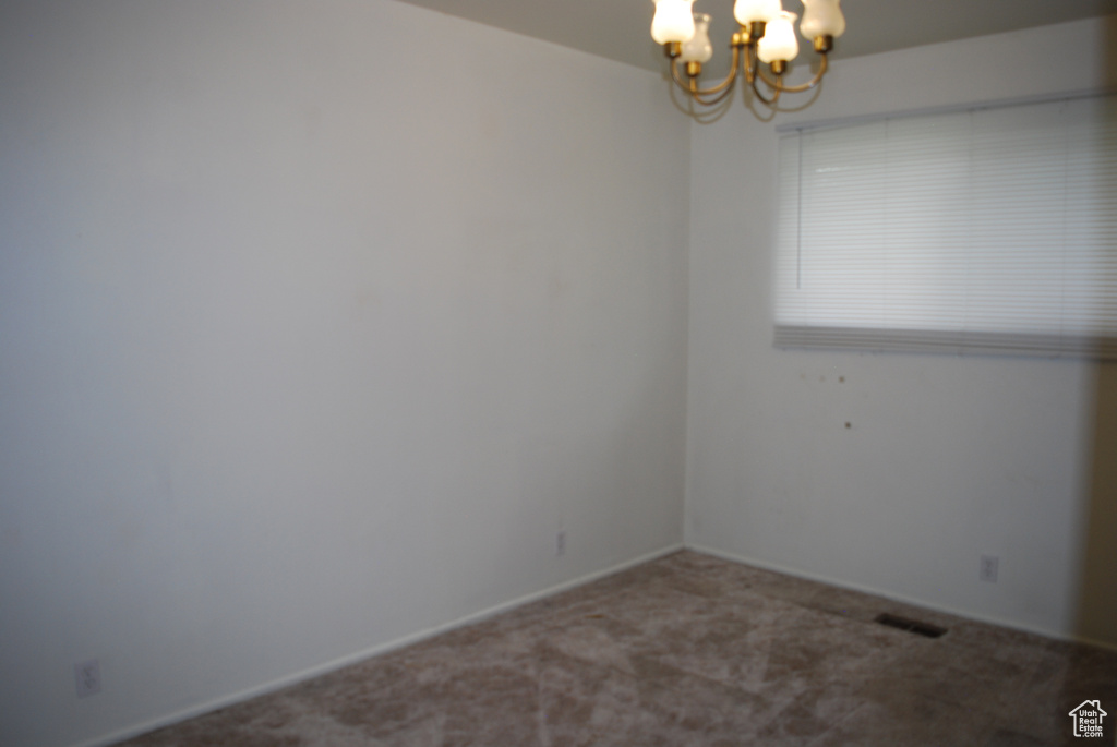 Empty room with carpet and a notable chandelier