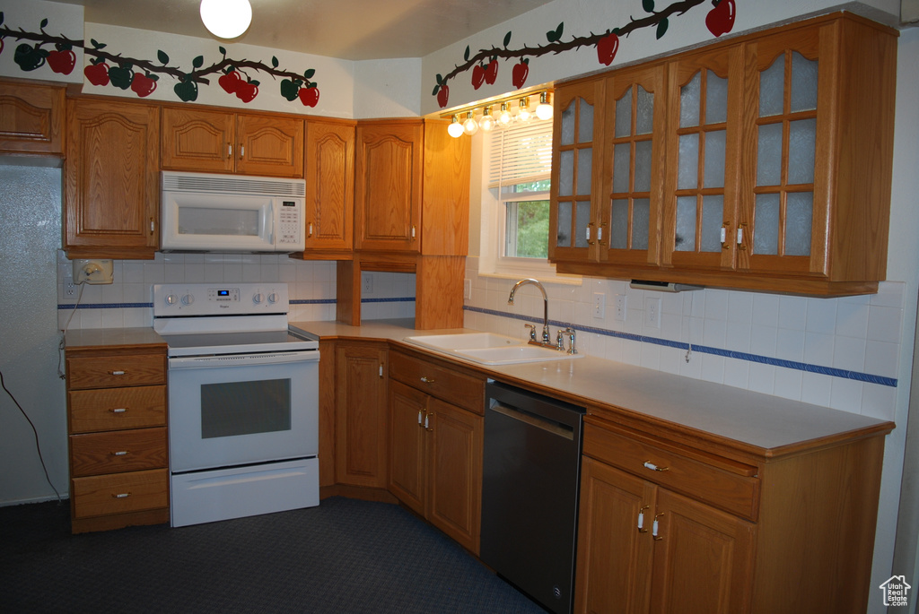 Kitchen featuring backsplash, white appliances, and sink
