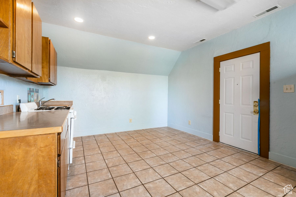Kitchen with sink, light tile floors, and vaulted ceiling