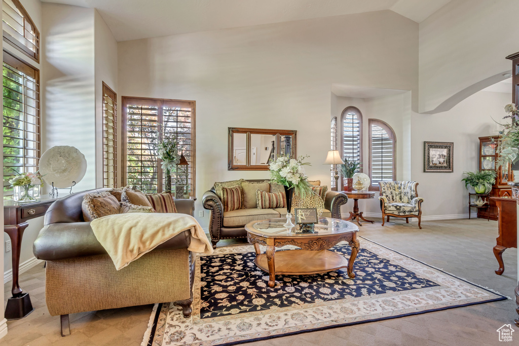 Living room with high vaulted ceiling, a wealth of natural light, and light carpet