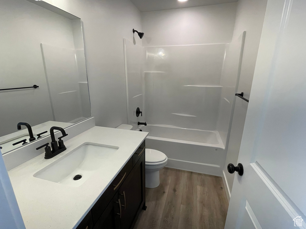 Full bathroom featuring vanity with extensive cabinet space, shower / bath combination, wood-type flooring, and toilet