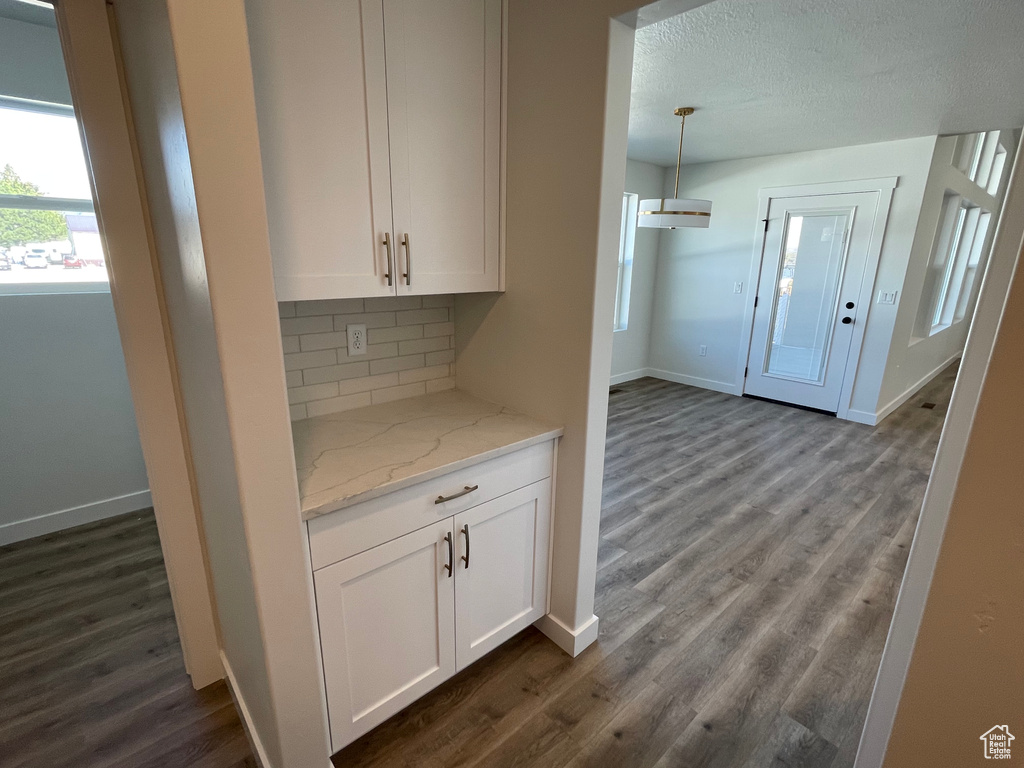 Kitchen with backsplash, dark hardwood / wood-style flooring, and white cabinetry