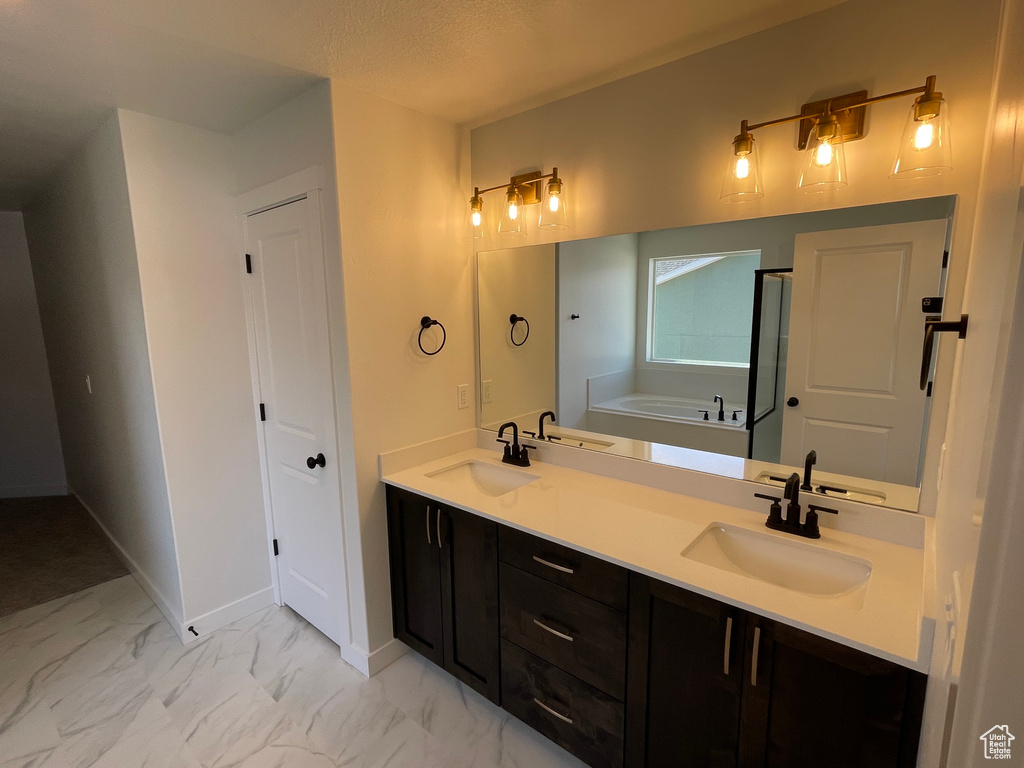 Bathroom featuring tile floors, large vanity, a washtub, dual sinks, and a textured ceiling