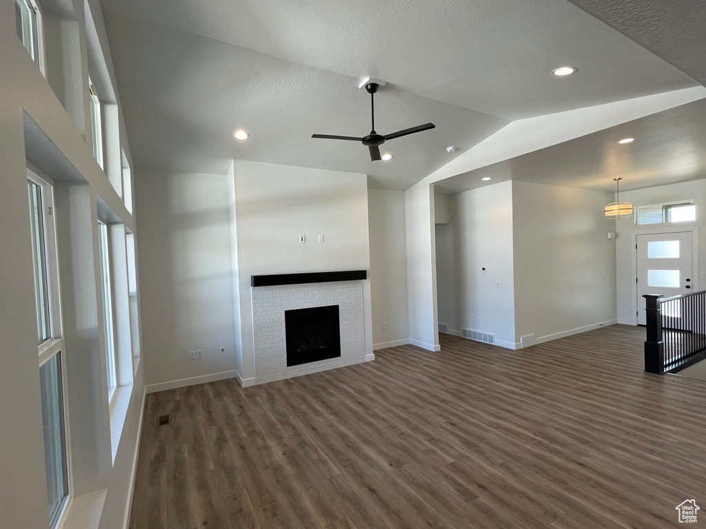 Unfurnished living room featuring high vaulted ceiling, ceiling fan, dark hardwood / wood-style floors, and a fireplace