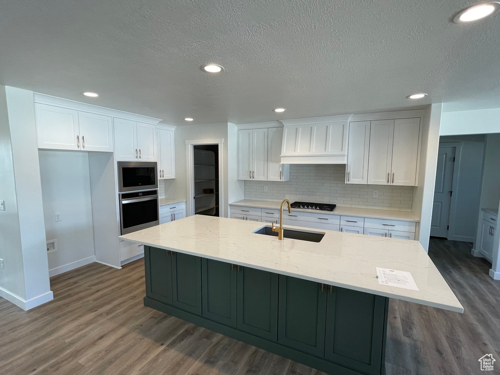 Kitchen featuring appliances with stainless steel finishes, hardwood / wood-style flooring, and a kitchen island with sink