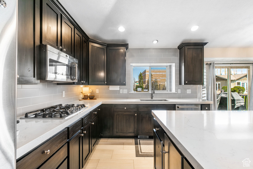 Kitchen featuring tasteful backsplash, dark brown cabinets, stainless steel appliances, and sink