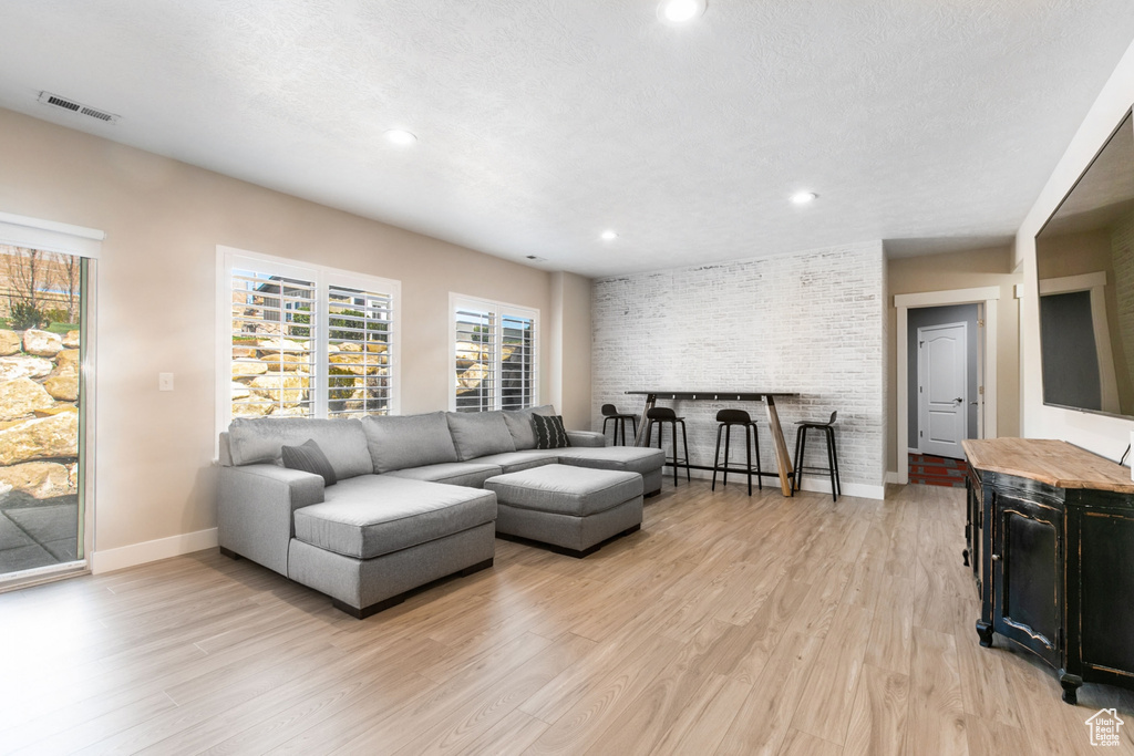Living room featuring brick wall, light hardwood / wood-style flooring, and a textured ceiling