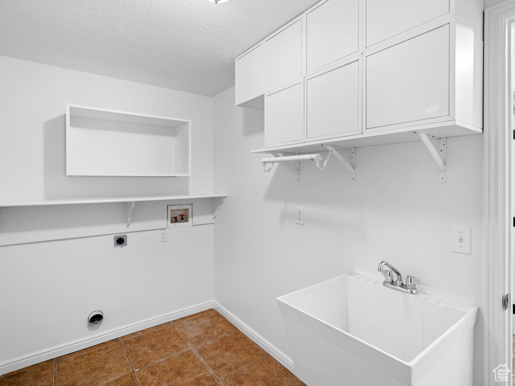 Laundry area featuring tile flooring, a textured ceiling, sink, electric dryer hookup, and washer hookup