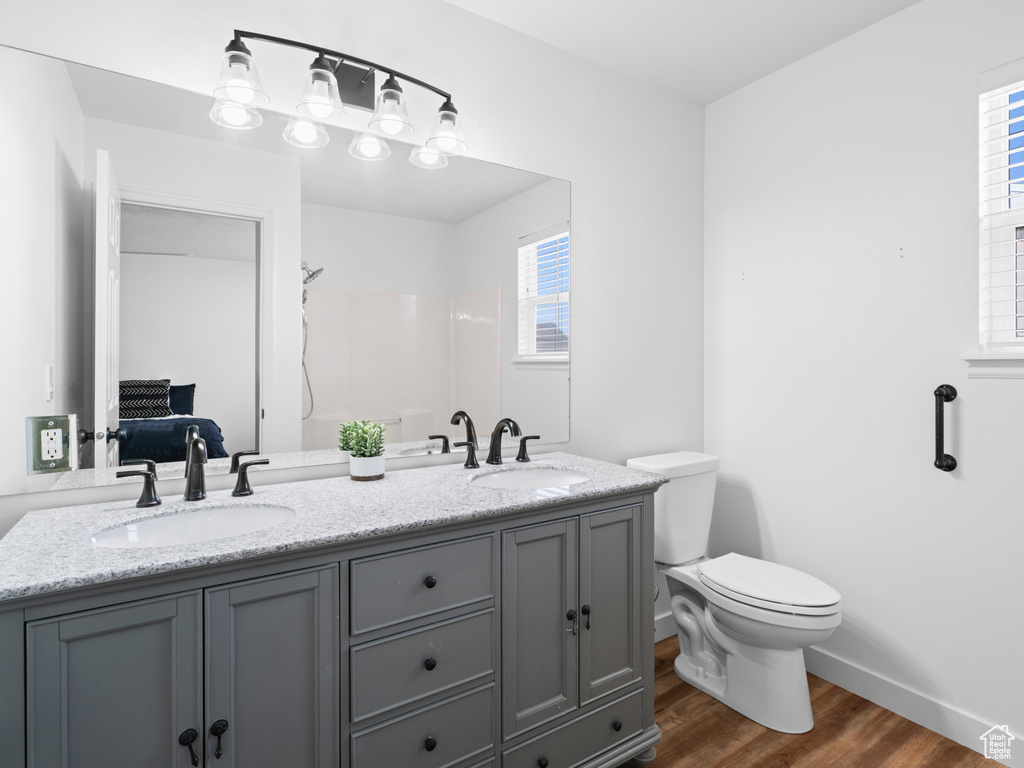 Bathroom featuring dual bowl vanity, toilet, and hardwood / wood-style flooring