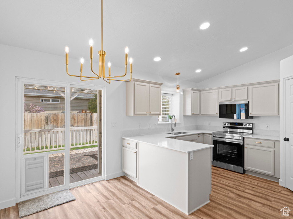 Kitchen with light hardwood / wood-style flooring, stainless steel appliances, lofted ceiling, sink, and pendant lighting