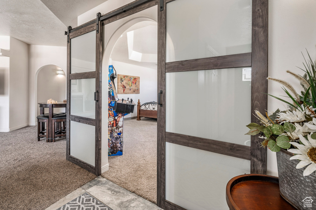 Hall featuring a barn door, a textured ceiling, and carpet floors