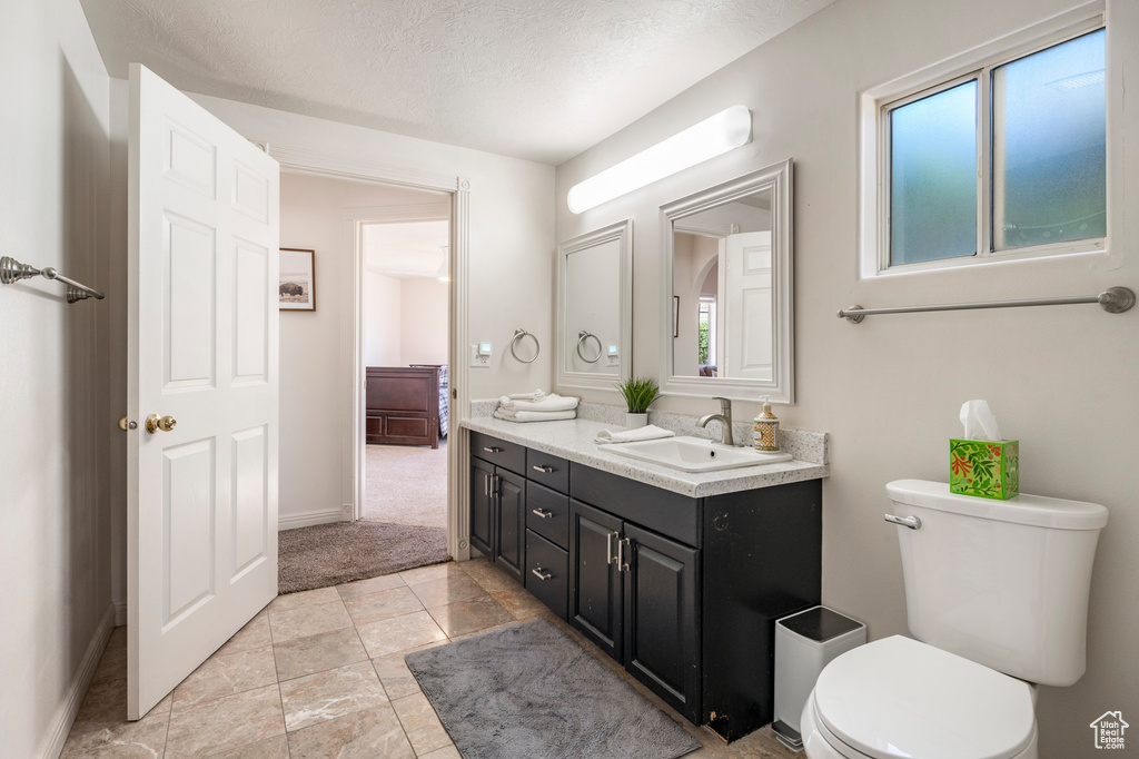 Bathroom featuring tile floors, toilet, a wealth of natural light, and a textured ceiling