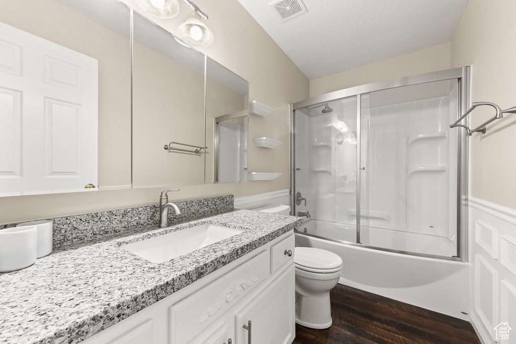 Full bathroom featuring vanity, hardwood / wood-style flooring, toilet, and bath / shower combo with glass door
