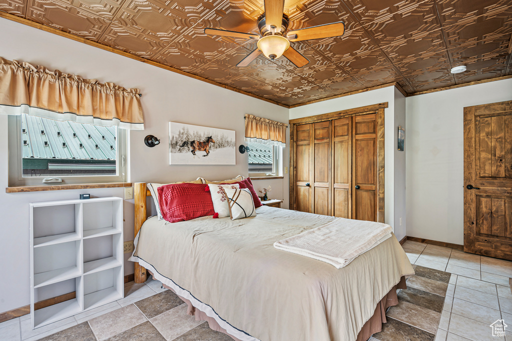 Tiled bedroom featuring ornamental molding, ceiling fan, and a closet