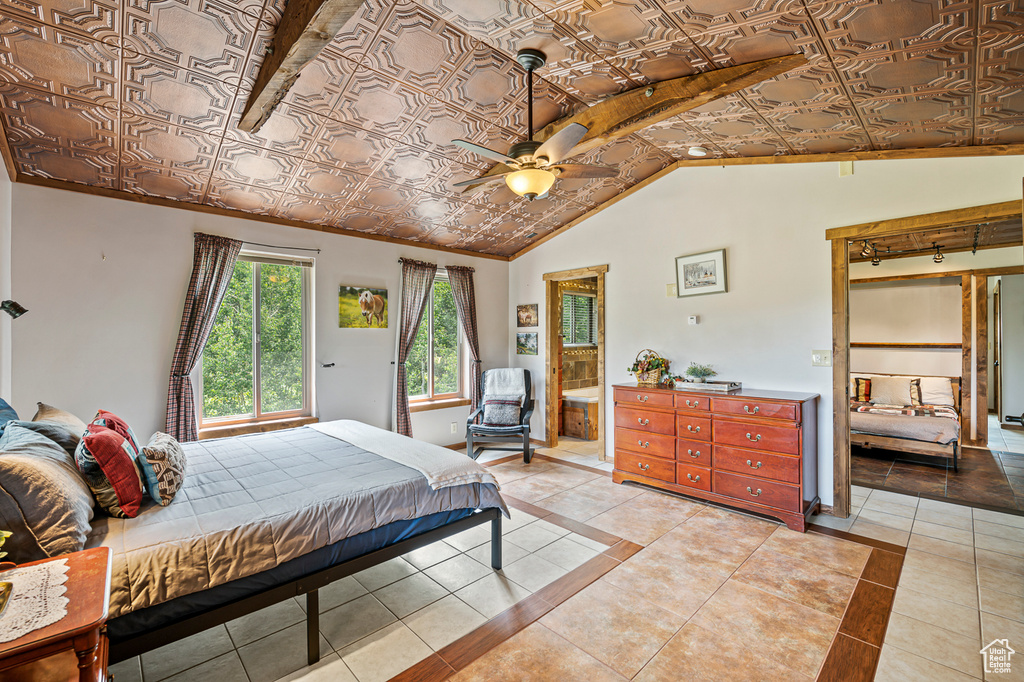 Tiled bedroom with connected bathroom, ceiling fan, and lofted ceiling