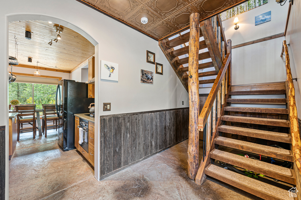 Stairs with crown molding, concrete floors, and wooden ceiling
