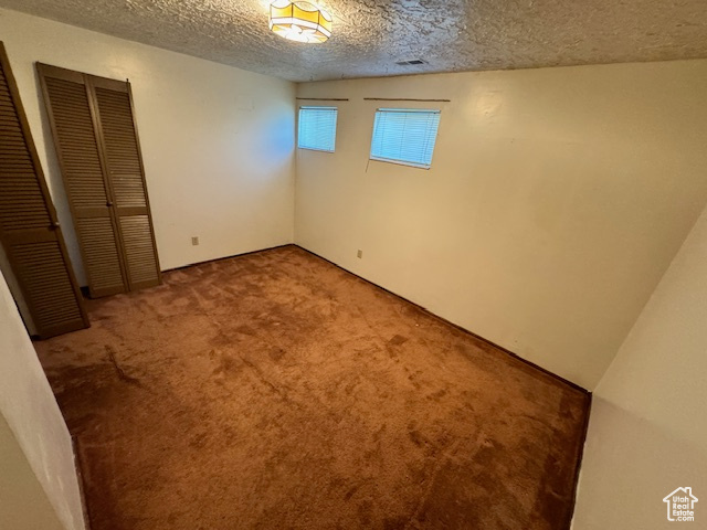 Unfurnished bedroom featuring a textured ceiling and carpet